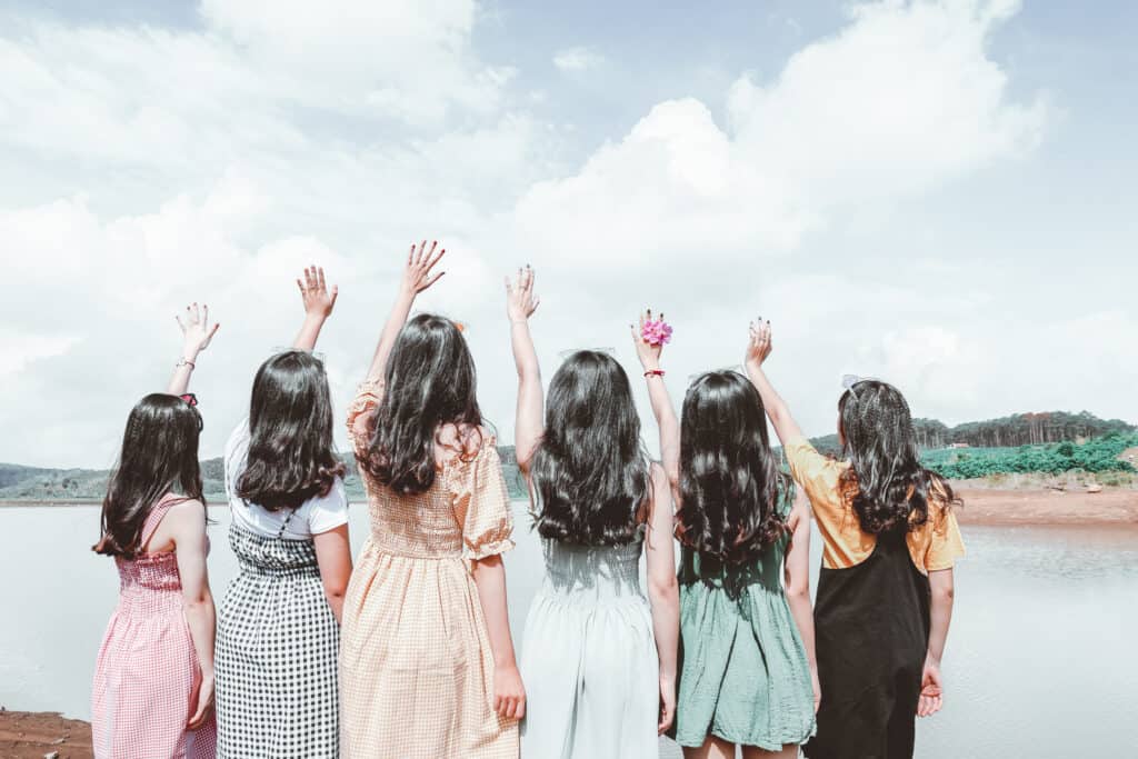 A group of girls standing raising their hands to the sky